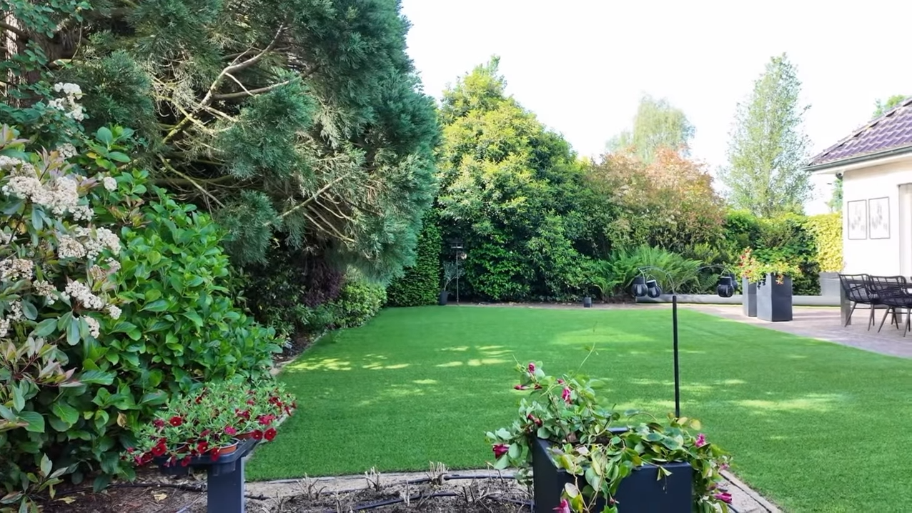 Groene tuin met bloembedden en terrasstoelen
