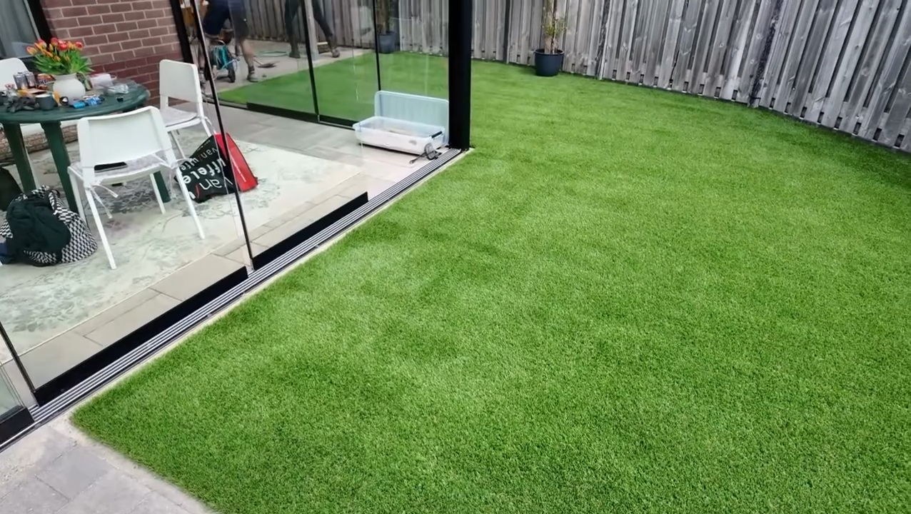 Tuin met kunstgras en glazen schuifdeuren.